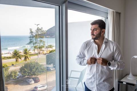 noivo abotoa camisa paisagem praia '