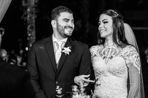 noivos se observam sorrindo no altar frente ao pastor preto e branco'