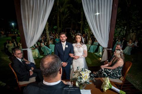 noivos atentos a cerimônia no altar frente ao pastor familiares observam'