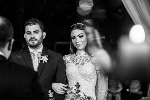 noivos atentos a cerimônia no altar frente ao pastor preto e branco'