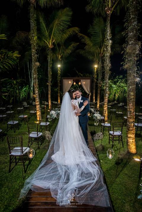 noivos posam altar ao fundo ambiente externo vegetação gramado coqueiros '