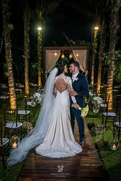 noivos posam altar ao fundo ambiente externo vegetação gramado coqueiros '
