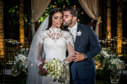 noivos posam altar ao fundo ambiente externo vegetação gramado coqueiros '