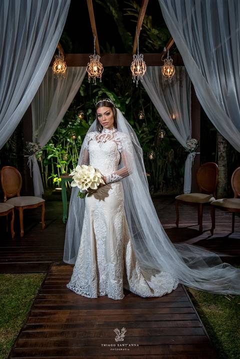 noiva sorri vestido renda véu buque copo de leite vegetação ao fundo '