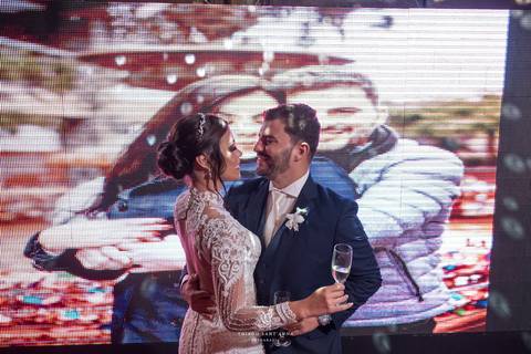 noivos dançam em frente a telão'