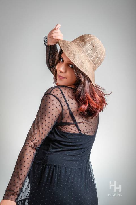 ensaio indoor ensaio interno em Brasília ensaio de gestante com chapéu no fundo branco ensaio em estúdio Brasília ensaio de gravidez foto de gestante em fundo branco sorrindo de lado para a câmera em Brasília '