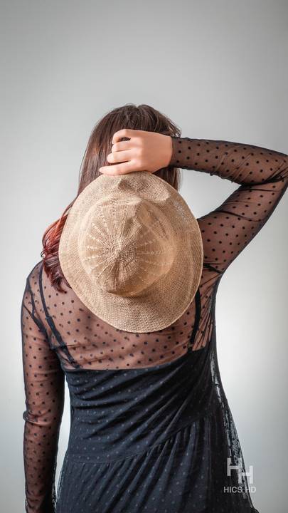 ensaio indoor ensaio interno em Brasília ensaio de gestante com chapéu no fundo branco ensaio em estúdio Brasília ensaio de gravidez foto de gestante em fundo branco de costas segurando chapéu em Brasília'