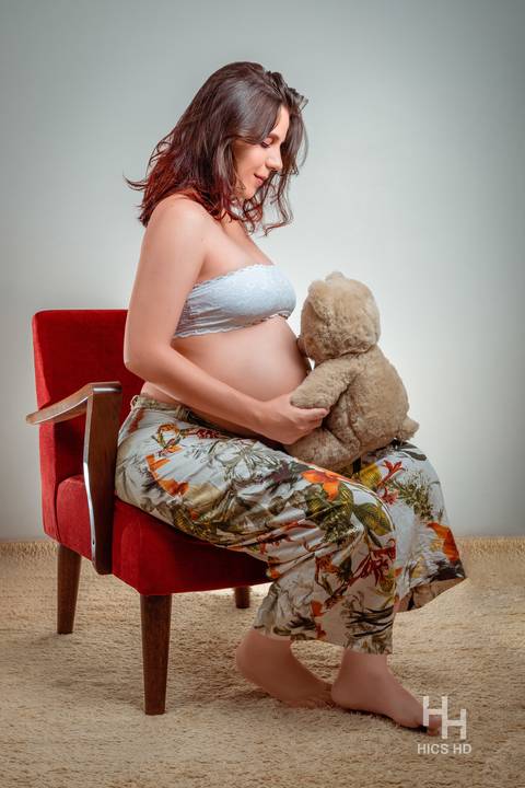 ensaio indoor ensaio interno em Brasília ensaio de gestante sentada em poltrona e brincando com o ursinho ensaio de gravidez foto de gestante em estúdio em Brasília'