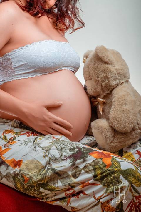 ensaio indoor ensaio interno em Brasília ensaio de gestante sentada em poltrona close com beijo do ursinho ensaio de gravidez  foto de gestante em estúdio em Brasília'