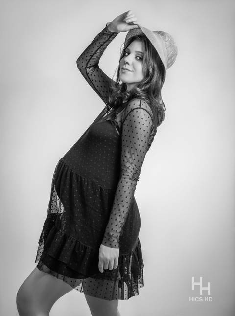 ensaio indoor ensaio interno em Brasília ensaio de gestante com chapéu no fundo branco ensaio em estúdio Brasília ensaio de gravidez foto de gestante em preto e branco segurando chapéu ensaio de gravidez'