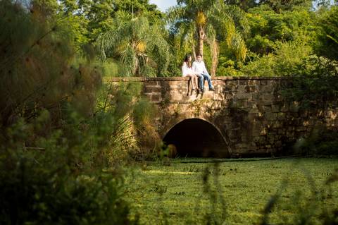 ensaio de casal da brenda e do sergio em um dia ensolarado nas ruas da cidade de ivoti nas casas eixamel fotografo de casal em sao leopoldo casal boeira sentados na ponte'