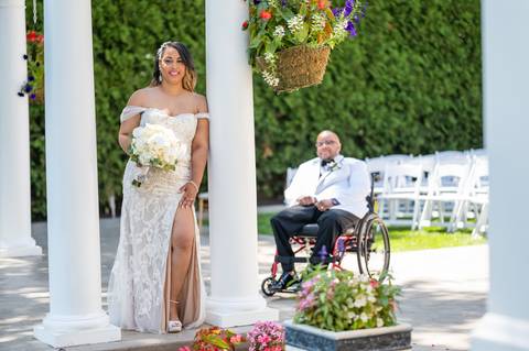 Photo by Vanessa Trettel,
Onsite wedding photographer at The Water View, Monroe, CT in July 2022.
It's an image of the bride standing with the bouquet and the groom behind sitting in the wheel chair with the river in the background'