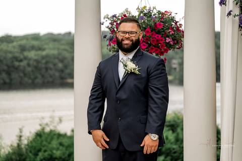 Briana & Nicholas share a joyful moment during their wedding at The Waterview in Monroe, CT. Surrounded by friends and family, they stand hand in hand, beaming with happiness as they exchange vows under a beautifully decorated arch'