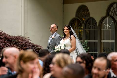 A lively wedding ceremony at The Waterview in Monroe, CT. A groomsman joyfully hands out beers to smiling guests, setting a fun and unique tone that perfectly matches the joyful personalities of Briana & Nicholas.'