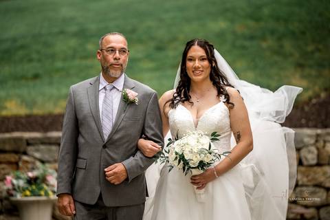 Briana & Nicholas share a joyful moment during their wedding at The Waterview in Monroe, CT. Surrounded by friends and family, they stand hand in hand, beaming with happiness as they exchange vows under a beautifully decorated arch'
