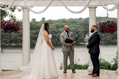 A lively wedding ceremony at The Waterview in Monroe, CT. A groomsman joyfully hands out beers to smiling guests, setting a fun and unique tone that perfectly matches the joyful personalities of Briana & Nicholas.'