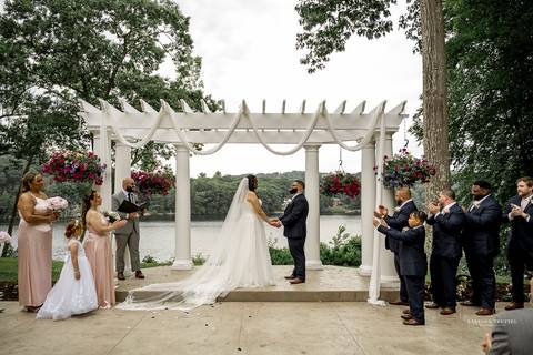 Captured in golden light, Briana & Nicholas steal a quiet moment together at The Waterview in Monroe, CT. The serene lake in the background enhances the romantic atmosphere as they embrace, lost in the love and joy of their special day.'