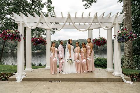 Briana & Nicholas share a joyful moment during their wedding at The Waterview in Monroe, CT. Surrounded by friends and family, they stand hand in hand, beaming with happiness as they exchange vows under a beautifully decorated arch'