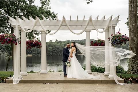 A lively wedding ceremony at The Waterview in Monroe, CT. A groomsman joyfully hands out beers to smiling guests, setting a fun and unique tone that perfectly matches the joyful personalities of Briana & Nicholas.'