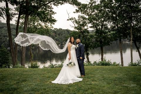 Briana & Nicholas share a joyful moment during their wedding at The Waterview in Monroe, CT. Surrounded by friends and family, they stand hand in hand, beaming with happiness as they exchange vows under a beautifully decorated arch'