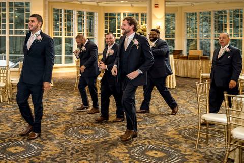 Briana & Nicholas share a joyful moment during their wedding at The Waterview in Monroe, CT. Surrounded by friends and family, they stand hand in hand, beaming with happiness as they exchange vows under a beautifully decorated arch'