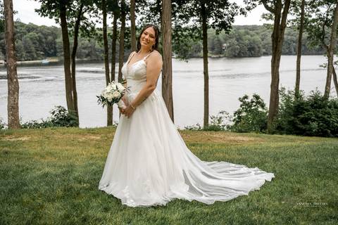 Captured in golden light, Briana & Nicholas steal a quiet moment together at The Waterview in Monroe, CT. The serene lake in the background enhances the romantic atmosphere as they embrace, lost in the love and joy of their special day.'