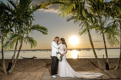 Jessica & Ben, a couple from California, embrace during their wedding at Anthony's Ocean View. The groom’s Connecticut roots are celebrated as they stand together, beaming with happiness under the glowing sunset sky.'