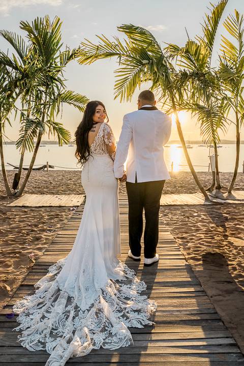 Jessica & Ben, a couple from California, embrace during their wedding at Anthony's Ocean View. The groom’s Connecticut roots are celebrated as they stand together, beaming with happiness under the glowing sunset sky.'