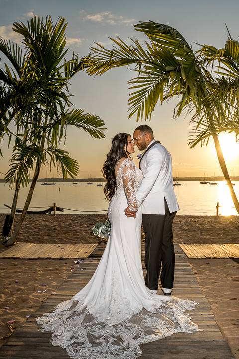 Captured in the soft glow of the setting sun, Jessica & Ben share a kiss at Anthony's Ocean View. The ocean and the vibrant sunset create a romantic atmosphere, making this moment feel truly magical.'
