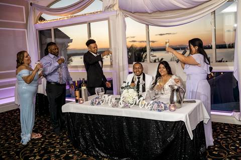 Jessica & Ben, a couple from California, embrace during their wedding at Anthony's Ocean View. The groom’s Connecticut roots are celebrated as they stand together, beaming with happiness under the glowing sunset sky.'