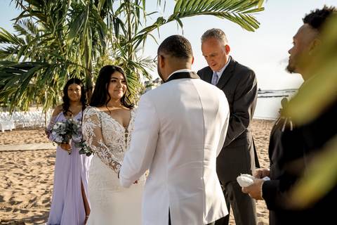 Captured in the soft glow of the setting sun, Jessica & Ben share a kiss at Anthony's Ocean View. The ocean and the vibrant sunset create a romantic atmosphere, making this moment feel truly magical.'