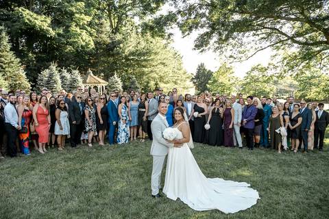The whole family posing together in front of the reception venue at Woodwinds, dressed in elegant wedding attire, radiating happiness.'