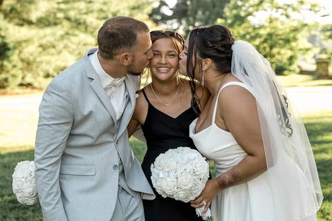 Sweet portrait of Amanda kissing her daughter’s forehead while Vinny wraps them both in a warm embrace.'