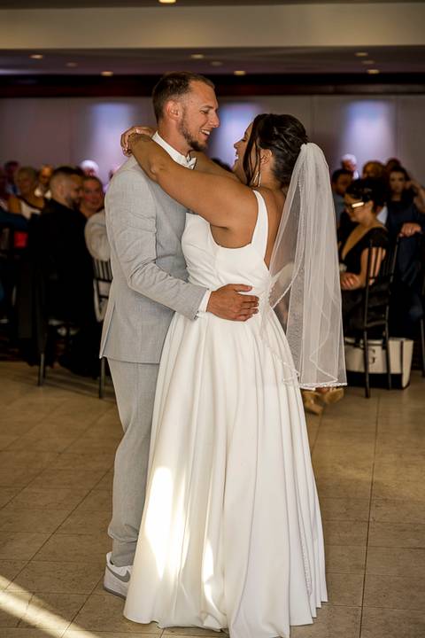 Amanda and Vinny sharing their first dance under twinkling lights at Woodwinds, smiling as guests watch with joy.'