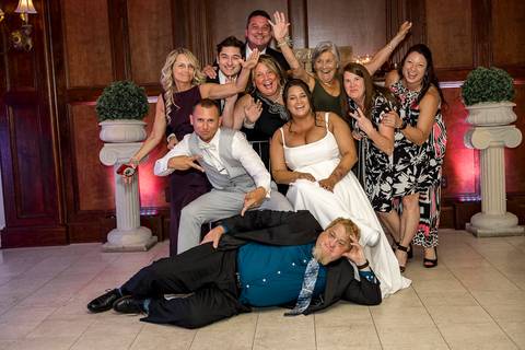 Bridesmaids and groomsmen letting loose on the dance floor, captured mid-laugh in a lively celebration moment.'