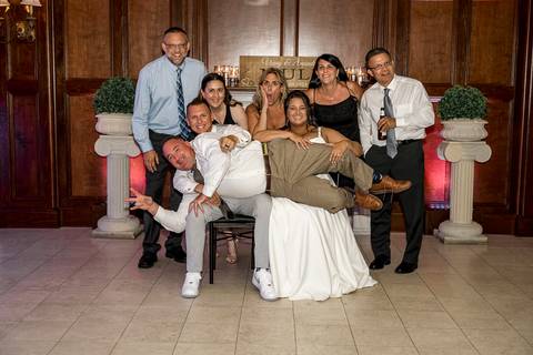 Bridesmaids and groomsmen letting loose on the dance floor, captured mid-laugh in a lively celebration moment.'