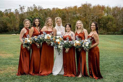 The newlyweds share a romantic first dance under twinkling lights at StoneHurst’s rustic barn, surrounded by cheering guests, while warm autumn colors fill the space with a cozy, festive atmosphere.'