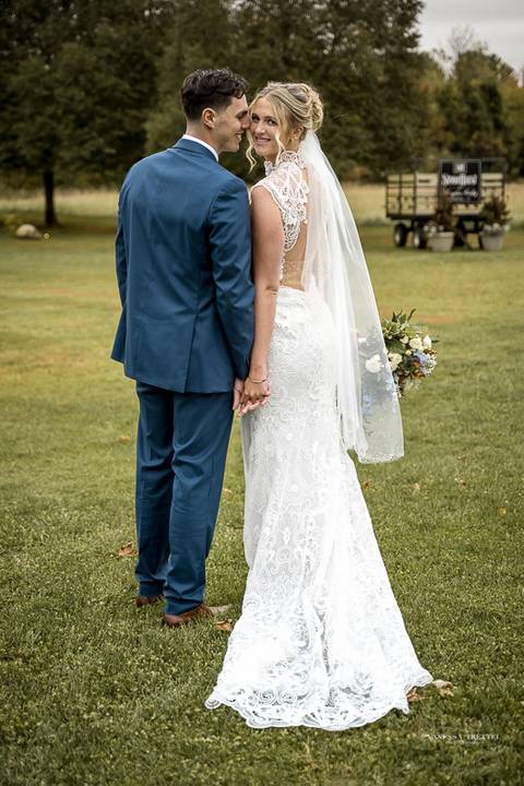 Cara walks down the aisle at St. James Catholic Church, her lace veil trailing behind as she beams with joy, surrounded by the church’s timeless architecture and a sea of emotional loved ones.'