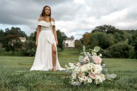 The bride poses with her lush pink-and-white bouquet, highlighting soft florals that perfectly match her romantic bridal look.'
