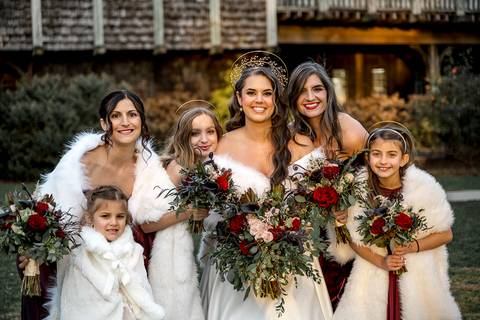 Laura laughs with her bridesmaids, all dressed in elegant winter hues, framed by the rustic charm of Bill Miller’s Castle, creating a moment of pure joy before the ceremony.'