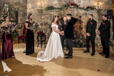 The newlyweds share a tender embrace by the grand stone fireplace of Bill Miller's Castle, the perfect backdrop for a winter wedding in Connecticut.'