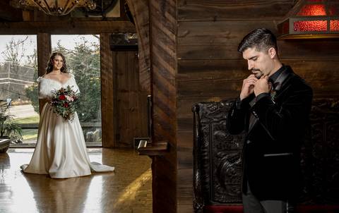 Lee ties his bowtie with a calm smile, surrounded by his groomsmen in the castle’s cozy prep room, capturing a timeless getting-ready moment.'