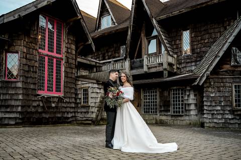 Framed by the towering castle doors, Laura and Lee hold each other close, their love illuminated by the soft winter light that highlights the timeless elegance of the venue.'