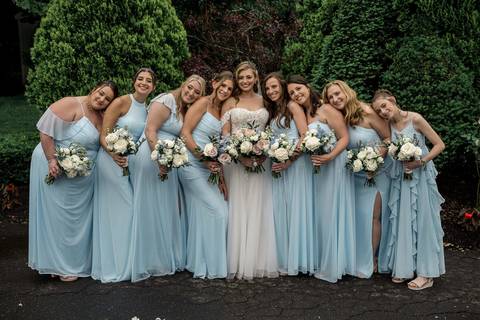 The bridal party bursts into laughter as they pose together, blending elegance with pure fun.'