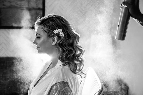 A candid moment of the bride surrounded by her bridesmaids, helping her into her elegant lace gown.'