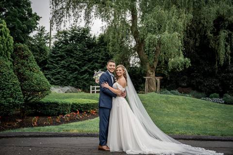 The newlyweds share a laugh as their veil catches the breeze, symbolizing the lightness of their love.'