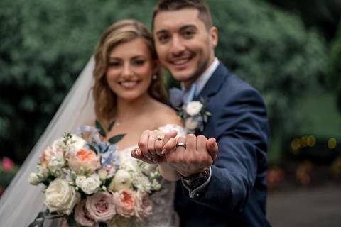 The newlyweds share a laugh as their veil catches the breeze, symbolizing the lightness of their love.'