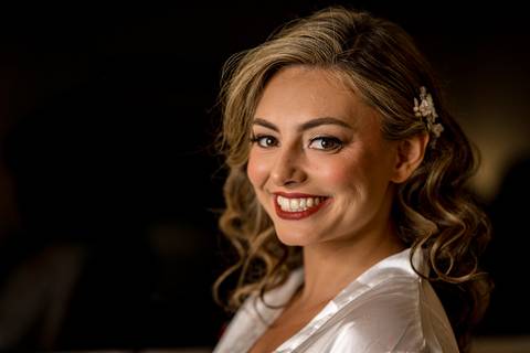 A candid moment of the bride surrounded by her bridesmaids, helping her into her elegant lace gown.'