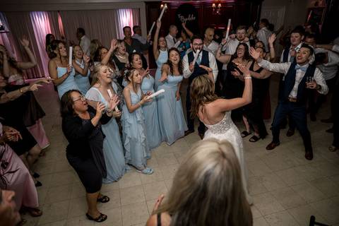 Guests fill the dance floor with high energy, hands in the air, and laughter echoing through the room.'