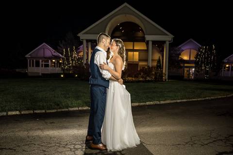 A romantic night shot of the couple under twinkling lights outside The Woodwinds.'